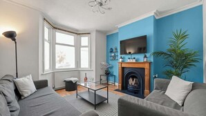 Ein modernes Wohnzimmer mit Kamin, grauen Sofas, einem Couchtisch und einem an der Wand montierten Fernseher.