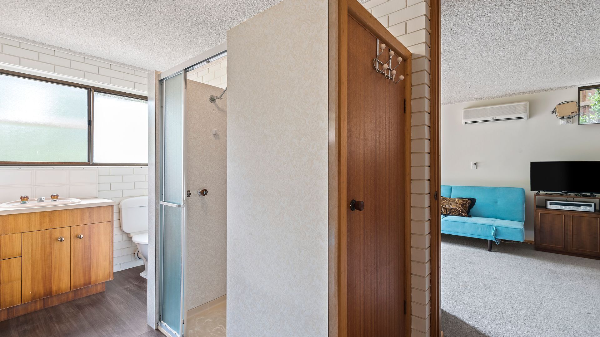 A compact living space with a bathroom, a kitchenette, and a seating area.