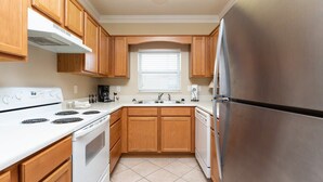 A kitchen with wooden cabinets, a white stove, a stainless steel refrigerator, and a window with blinds. - Riverfront Condo Pigeon Forge/Mt. LeConte Views (Pigeon Forge)