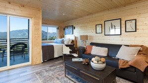 Une pièce comprenant un lit, un canapé, une table basse et offrant une vue sur les montagnes grâce à une porte coulissante.