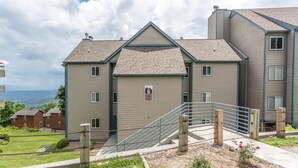 A multi-story residential building with a garage door, a staircase, and a view of the surrounding landscape. - Outstanding Mt. LeConte View/Indoor Pool & Hot Tub (Gatlinburg)