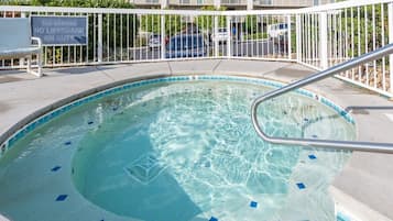 A swimming pool with a no diving sign, a lifeguard duty sign, and a metal railing.