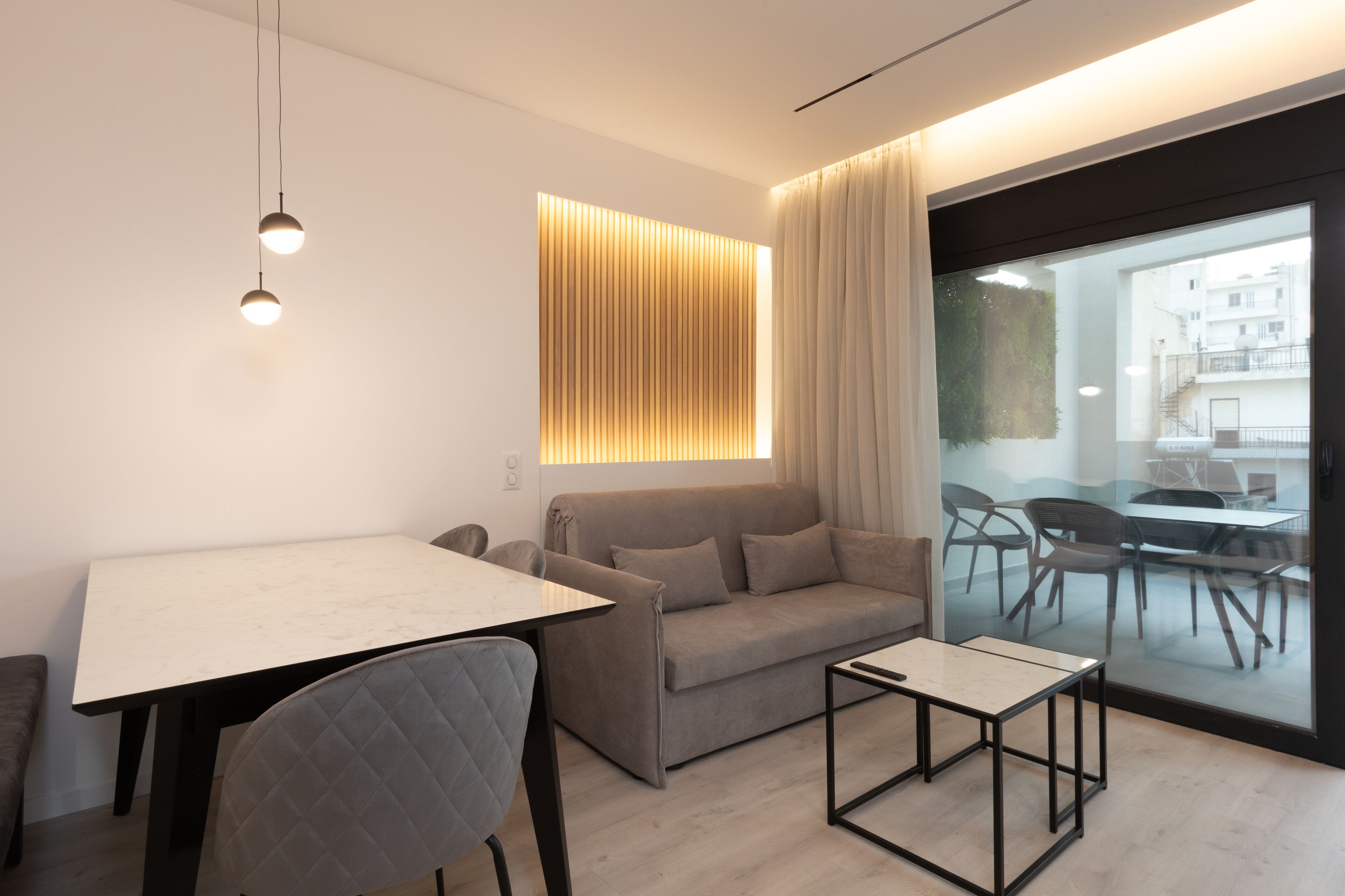 Un salon moderne avec un canapé, une table à manger et une cloison en verre.