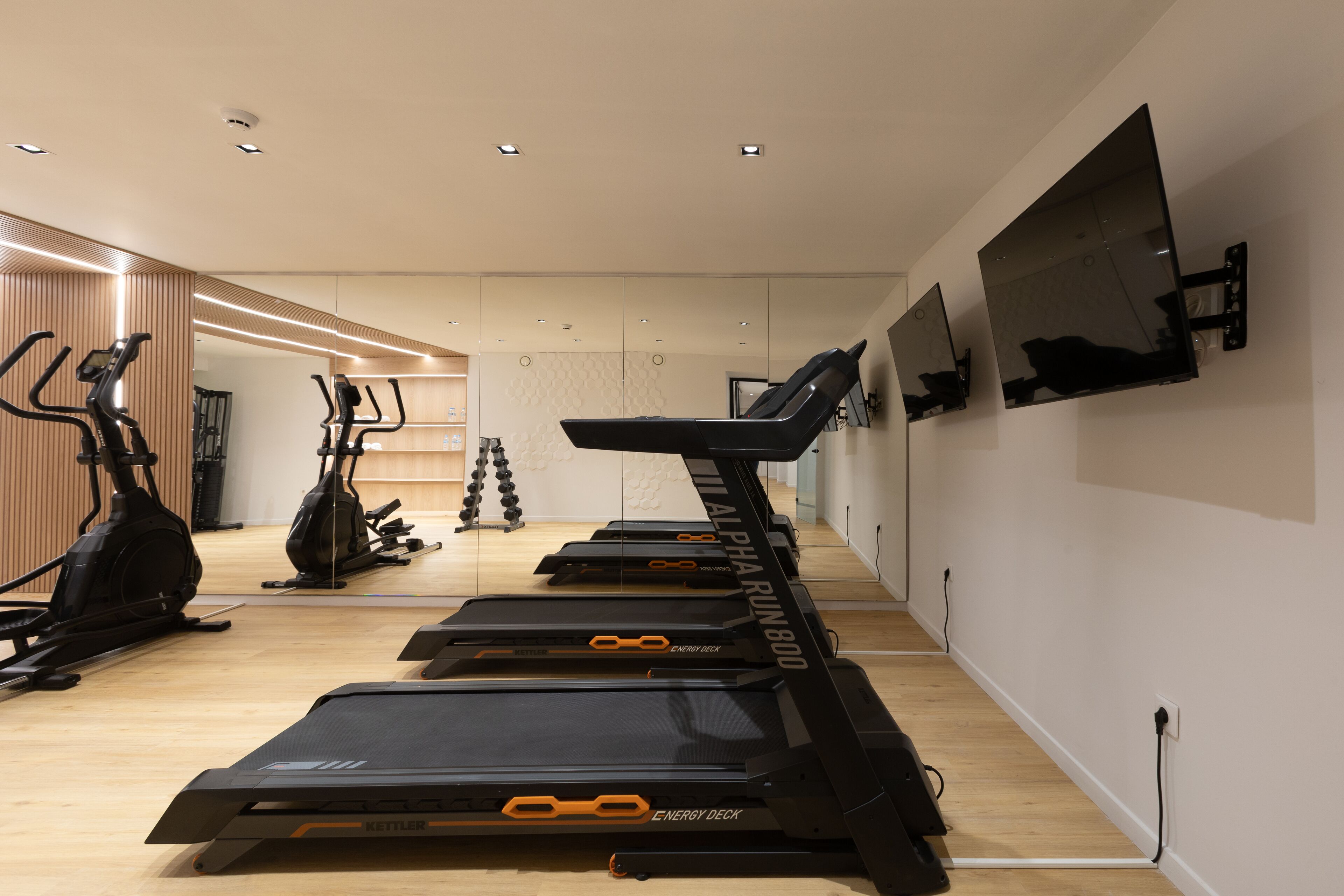 Un gimnasio con cintas de correr, bicicletas estáticas y elípticas.