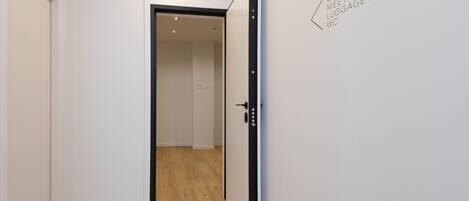 Pasillo que conduce a un gimnasio con salón de reuniones, piso de madera y puerta blanca.