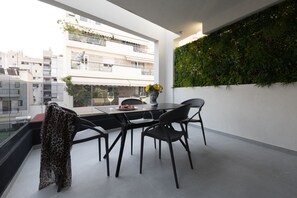Un espace repas moderne avec une table en verre, des chaises noires et un vase rempli de fleurs jaunes.