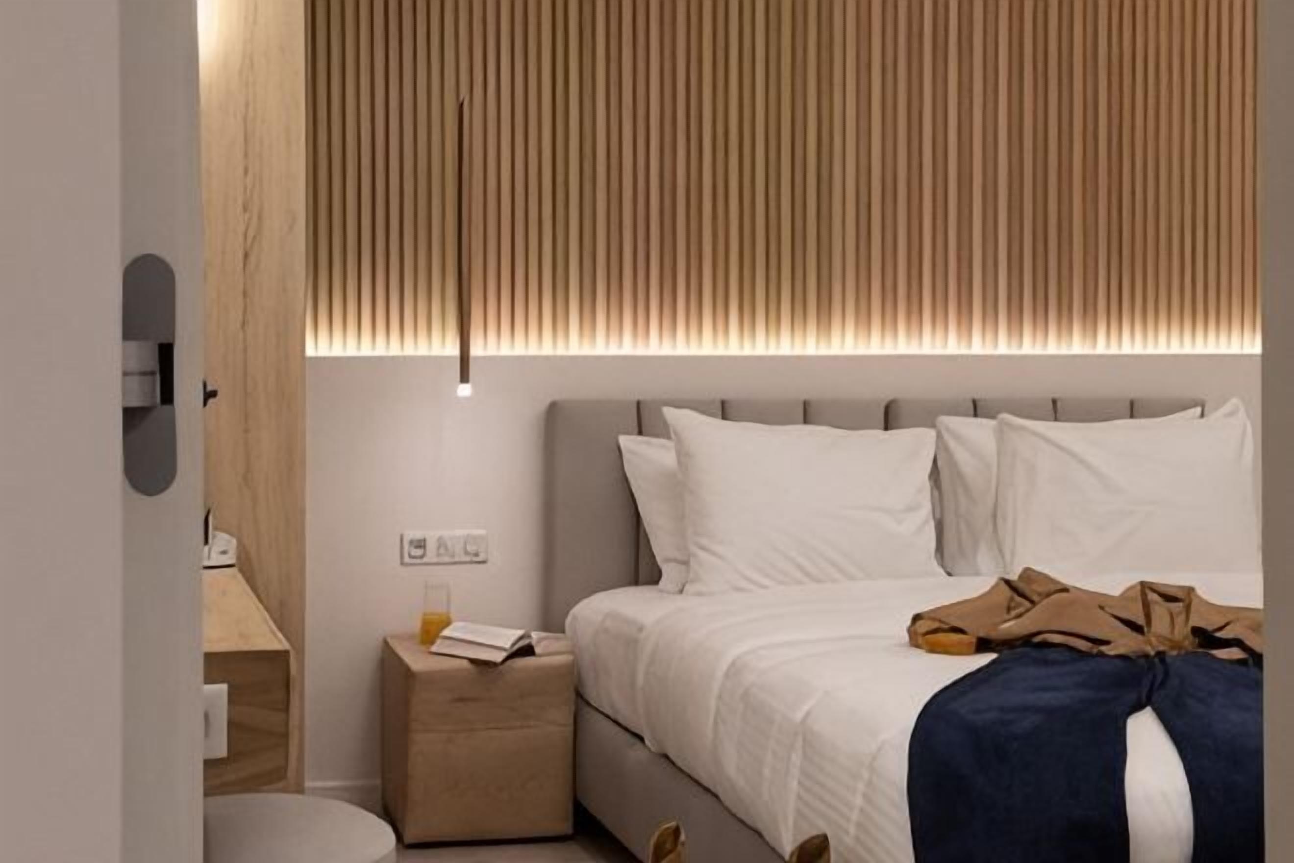 Ein modernes Hotelzimmer mit Bett, Nachttisch und Wandleuchte.