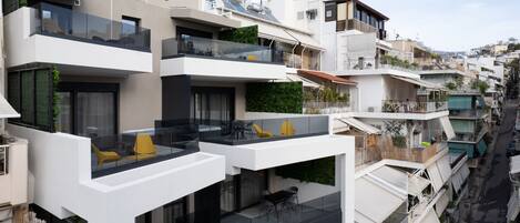 A multi-story residential building with balconies, outdoor seating, and solar panels.