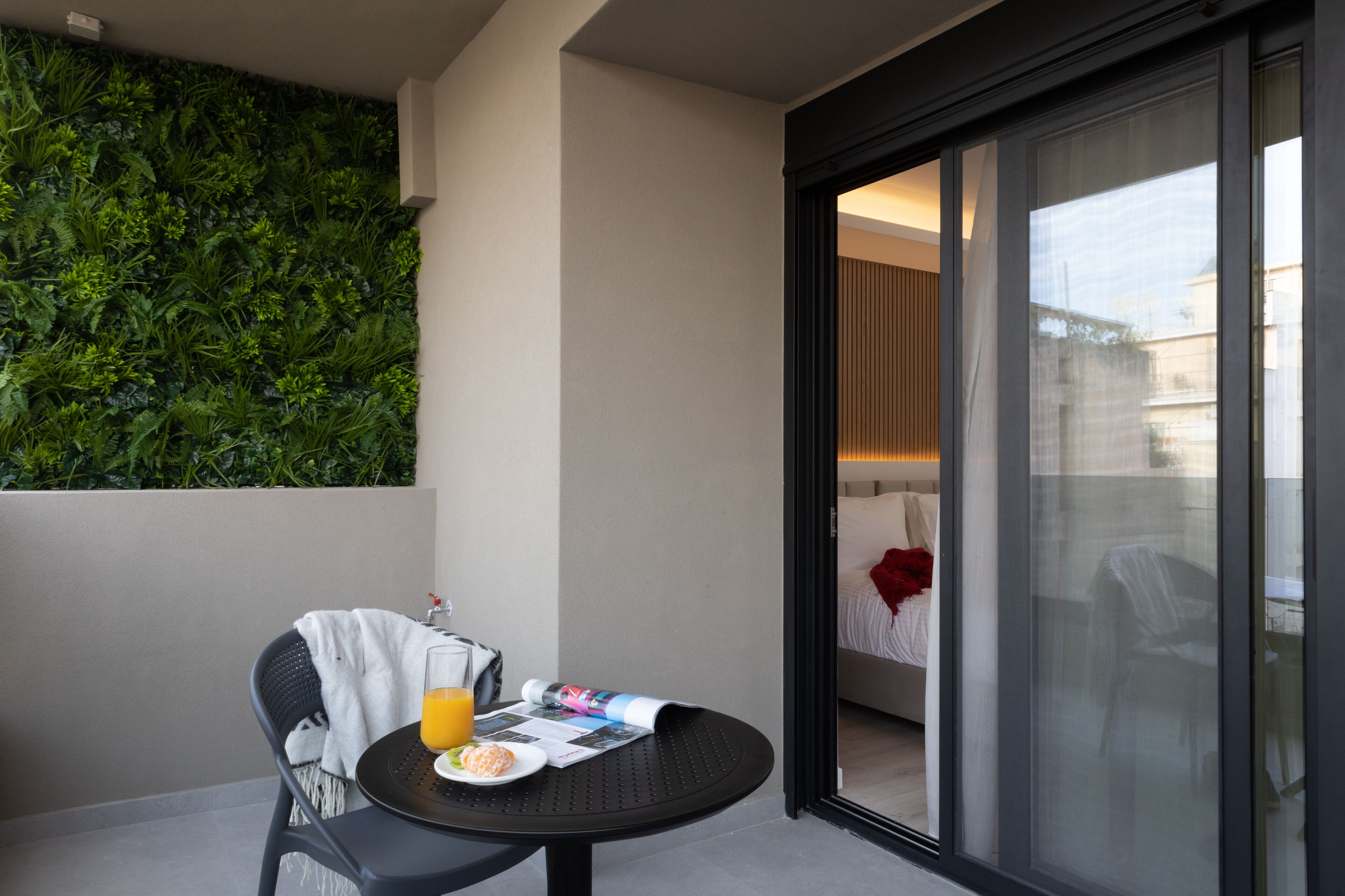 A balcony with a table, a chair, a glass of orange juice, and a meal.