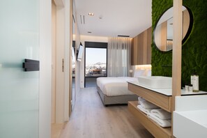 Une chambre d’hôtel moderne dotée d’un grand lit, d’une coiffeuse avec miroir et offrant une vue sur la ville grâce à une grande fenêtre.