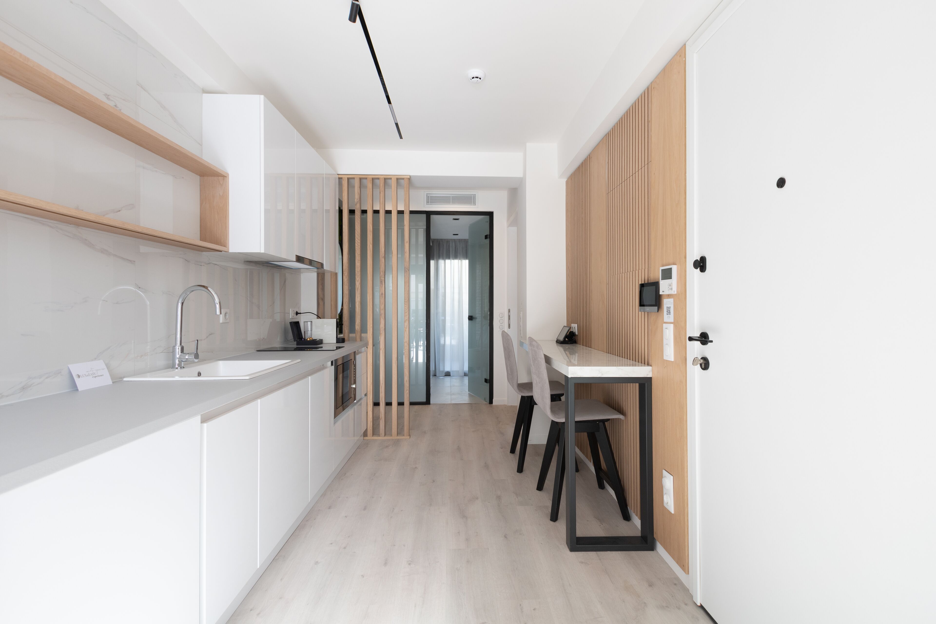 A modern kitchen with white cabinetry, a built-in sink, and a dining area with a table and chairs.