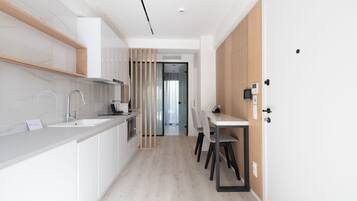 A modern kitchen with white cabinetry, a built-in sink, and a dining area with a table and chairs.