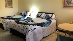 Una camera d'albergo con un letto grande, un comodino con una lampada e un tavolino rotondo.