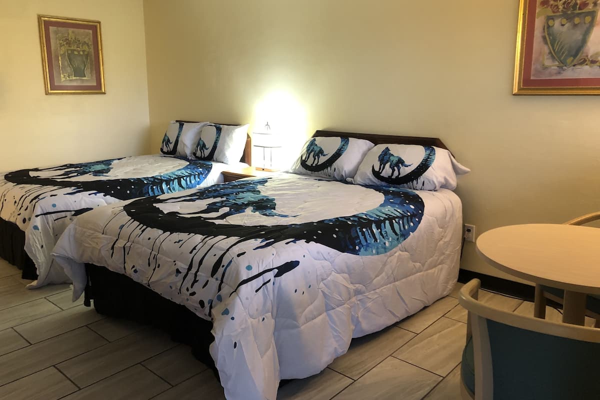A hotel room with a large bed, a bedside table with a lamp, and a small round table.