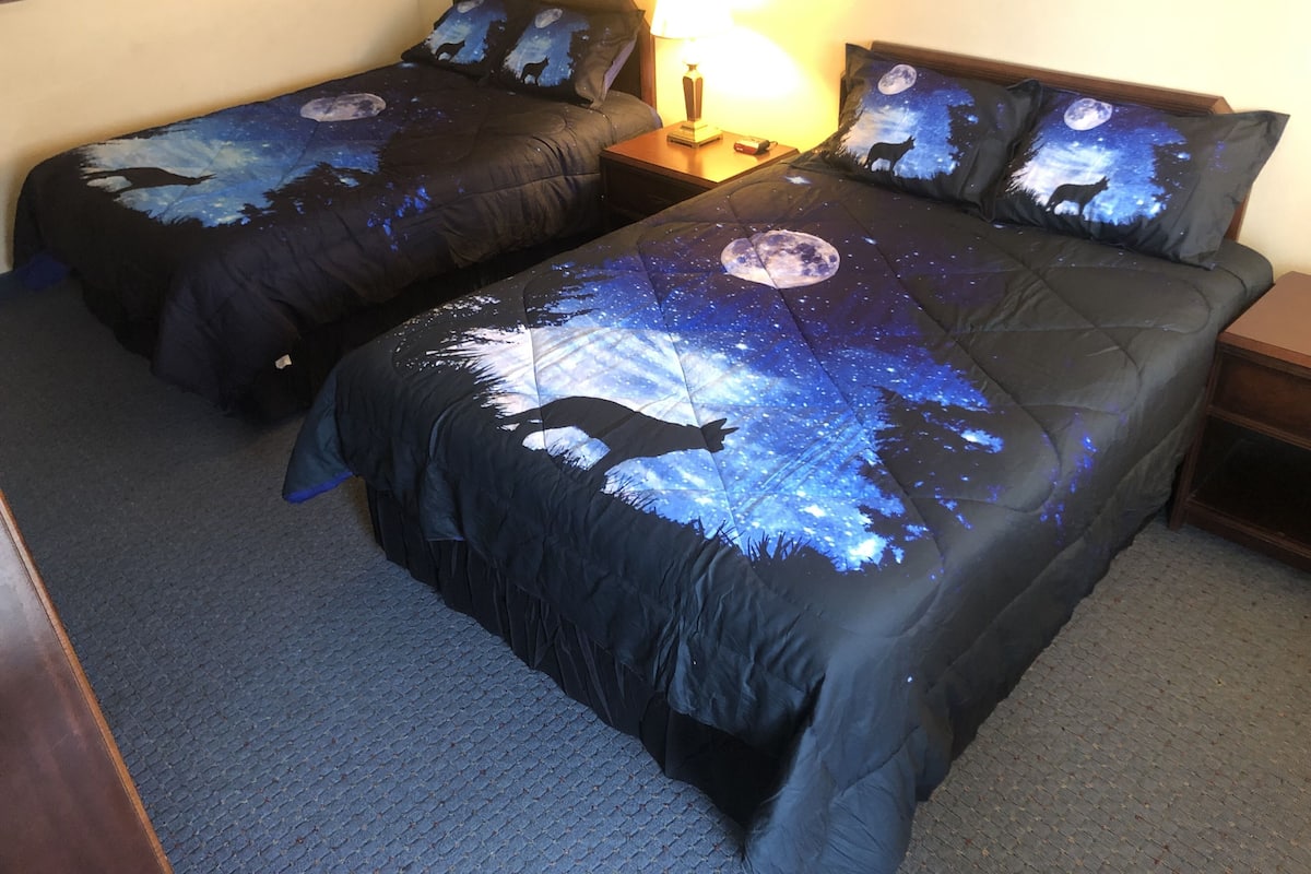 A double bed with a starry night sky design, two bedside tables, and a lamp.
