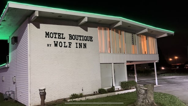 Un motel boutique con facciata bianca e luci al neon verdi.