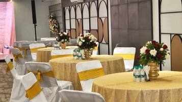 A conference room with round tables, white chairs with gold sashes, and floral centerpieces.