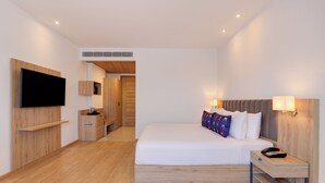 A modern hotel room with a large bed, bedside table, TV mounted on the wall, and a small desk area.