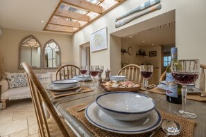A dining area with a wooden table, chairs, and a bottle of wine.