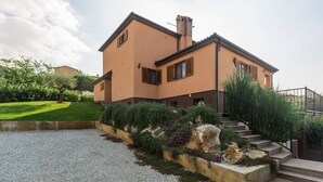 A two-story house with a gravel driveway, a stone retaining wall with plants, and a staircase leading to the entrance. - Villa Marina with pool, BBQ & parking near Poreč (Jasenovica)