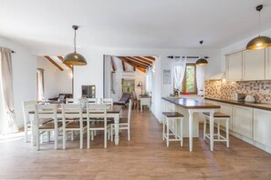 A spacious kitchen with a dining area, wooden flooring, and pendant lighting.