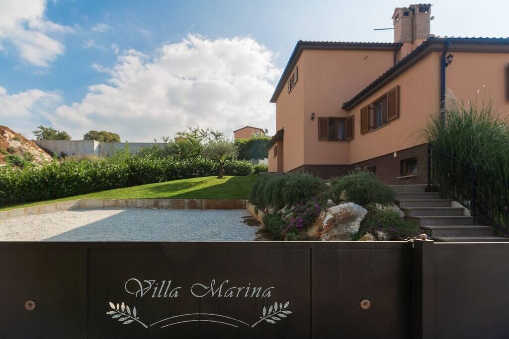 Villa Marina with a well-maintained garden, a gravel pathway, and a staircase leading to the entrance.