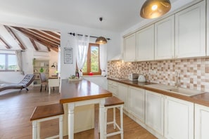 A kitchen with white cabinets, a wooden countertop, and a hanging pendant light.