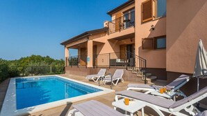 A poolside area with lounge chairs, a pool, and a building with balconies. - Villa Marina with pool, BBQ & parking near Poreč (Jasenovica)