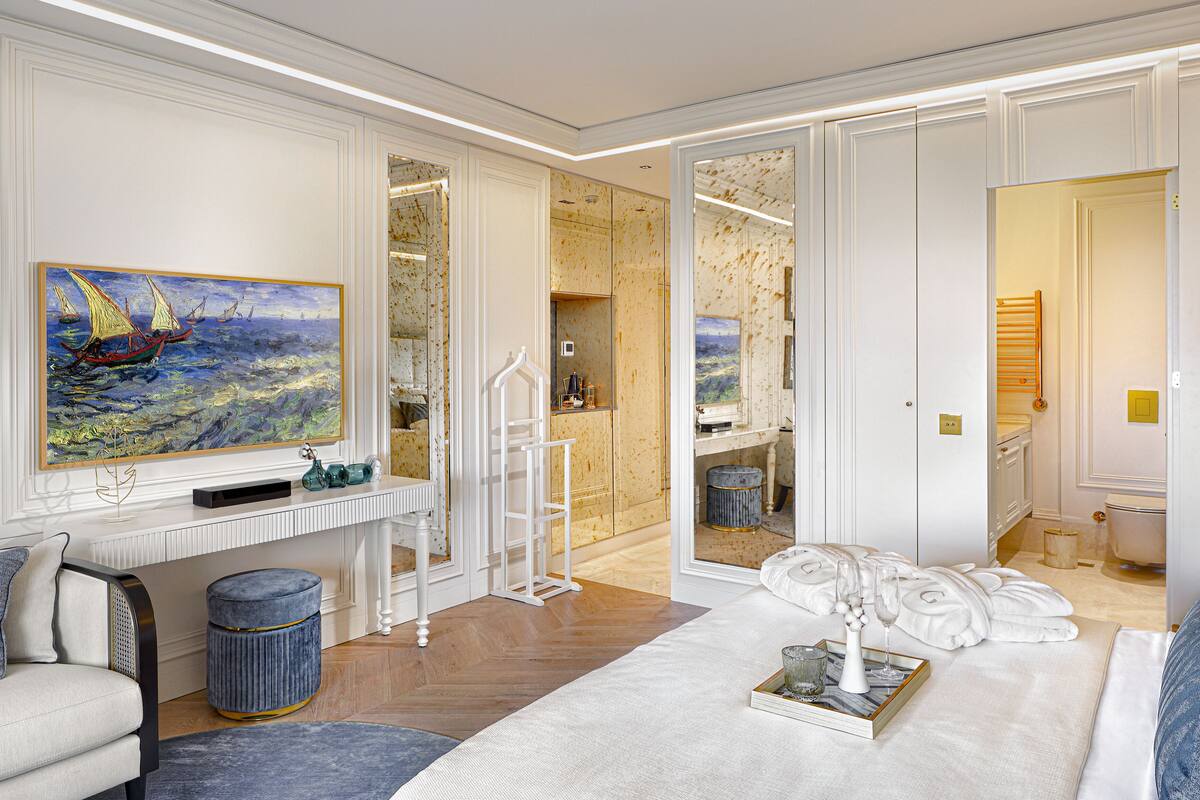 Une pièce spacieuse avec un grand tableau, une console blanche, un canapé et une grande fenêtre.