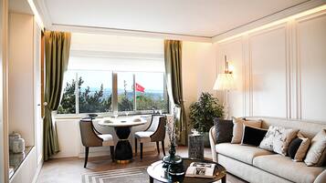 A modern living room with a sofa, a coffee table, a dining table with chairs, and a view of the city through large windows.
