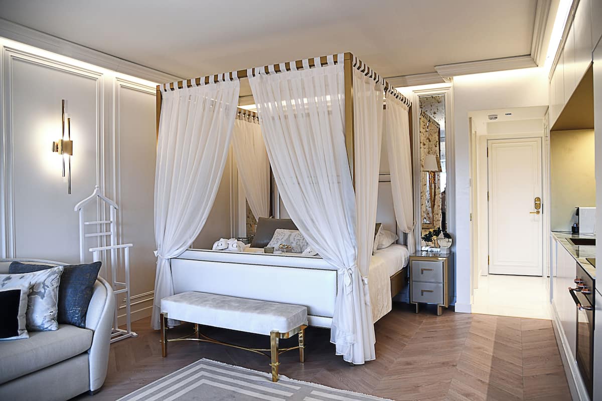 Une chambre à coucher avec un lit à baldaquin, une table de chevet, un banc, une commode et un miroir.