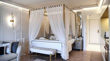 Um quarto com uma cama de dossel, uma mesa de cabeceira, um banquinho, um criado-mudo e um espelho.