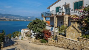 Ein Küstengebäude mit einer Steintreppe, die zu einem Balkon mit Meerblick führt.