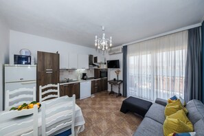 Un appartement moderne comprenant une cuisine, un coin repas et un salon. Il est équipé d’une table à manger avec des chaises, d’un canapé et d’un téléviseur.