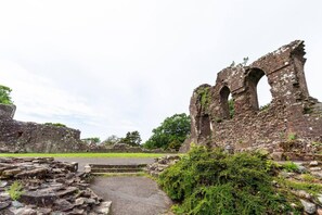 Ancient ruins with stone walls and arches, surrounded by greenery and a paved path. - Beautiful 2-bed House in Egremont Milo's Place (Egremont)