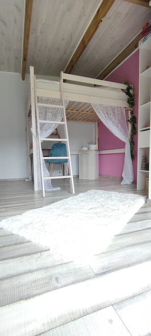 A room with a bunk bed, a ladder, a blue chair, a white rug, and a pink wall. - 3-bedroom house on the edge of a ravine, swimming pool  (Piton St leu)