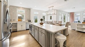 A modern kitchen with a central island, stainless steel appliances, and a large window providing natural light.