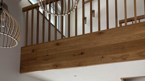 A spacious room with a wooden staircase, a large window with a view of a snowy landscape, and a round wall art of a deer. - Das Franz 1 (Weitnau)