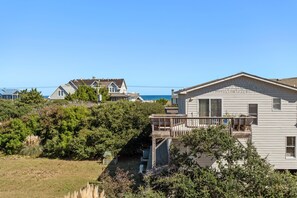 Eine Wohngegend an der Küste mit Häusern, einer Holzterrasse und Blick aufs Meer.