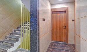 A modern interior with a marble staircase, a wooden door, and a tiled floor. - Treebo Merit (Indore)
