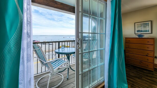Un balcón con vista al mar, una mesa con sillas y un aparador de madera.