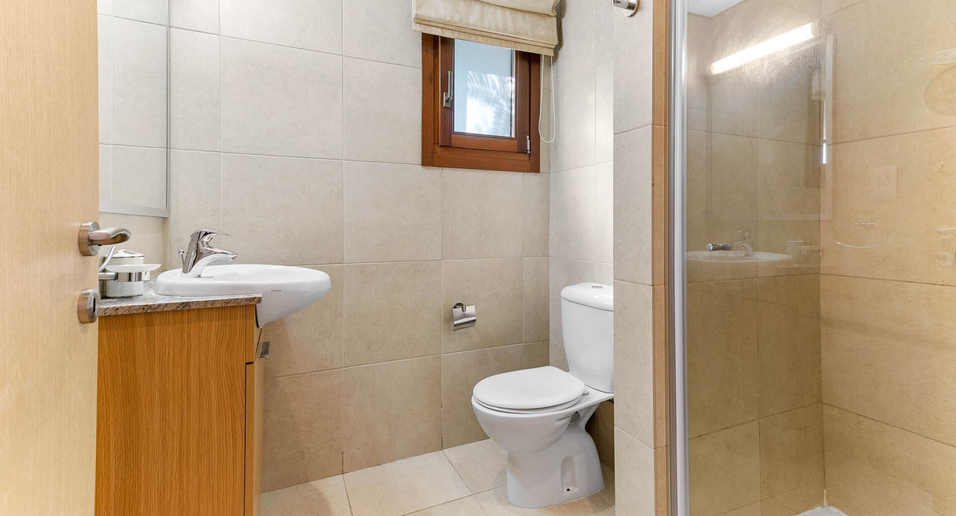 A small bathroom with a toilet, sink, and shower.