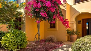 A yellow building with a large pink bougainvillea tree in front. - Apartment BH01 - Anthos (Kouklia)