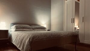 Une chambre à coucher avec un lit, des tables de chevet, une armoire et une lampe.