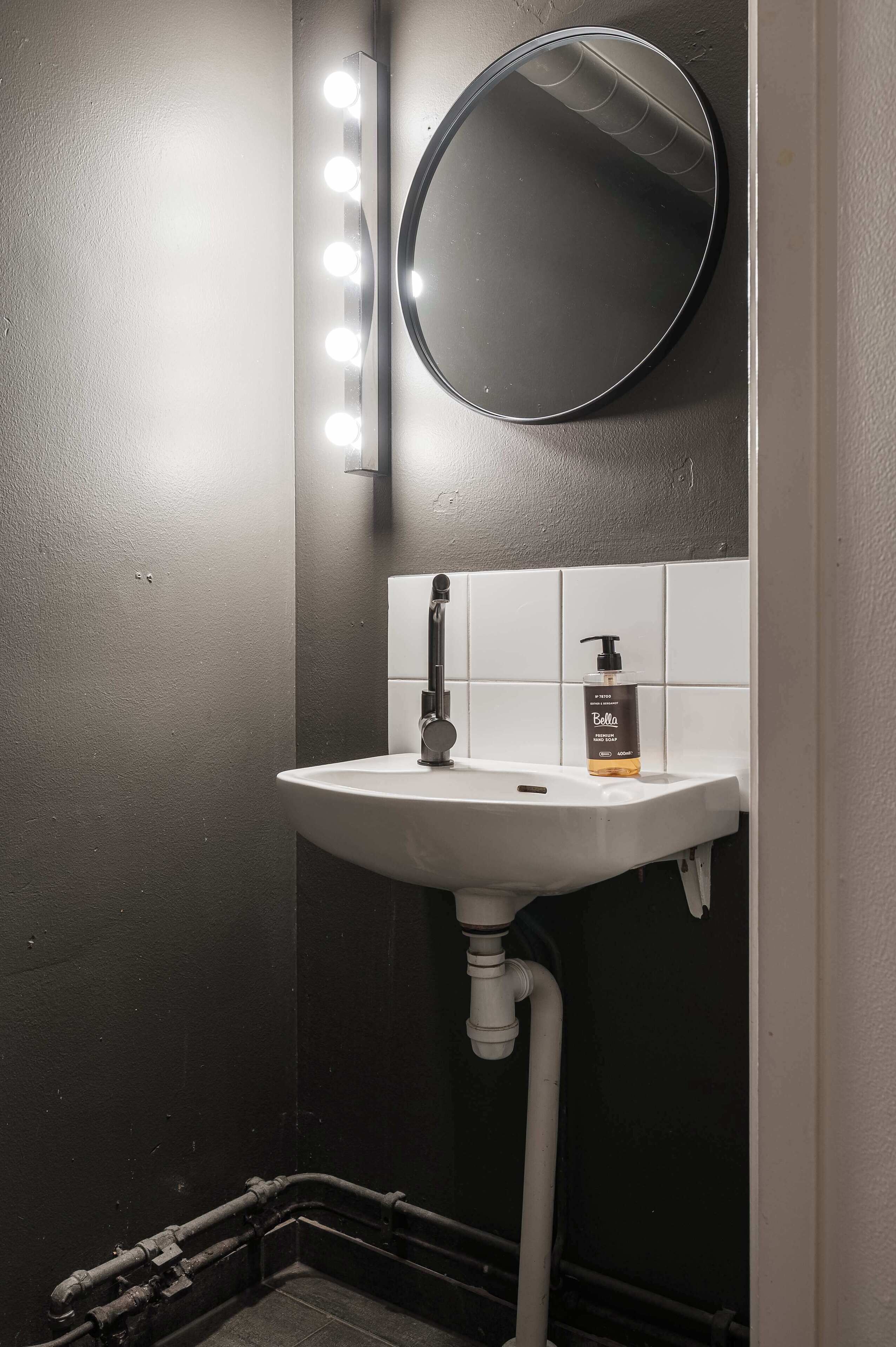 Ein Badezimmer mit einem weißen Waschbecken, einem beleuchteten Spiegel und einer Seife.