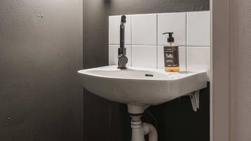 Ein Badezimmer mit einem weißen Waschbecken, einem beleuchteten Spiegel und einer Seife.