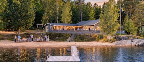 Eine Lodge am Seeufer mit Steg, Außenbereich und einem Gebäude mit überdachter Terrasse.