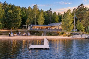 A lakeside lodge with a dock, outdoor seating, and a building with a covered patio. - The beach - Bockaberg Private Resort & SPA (Floda)
