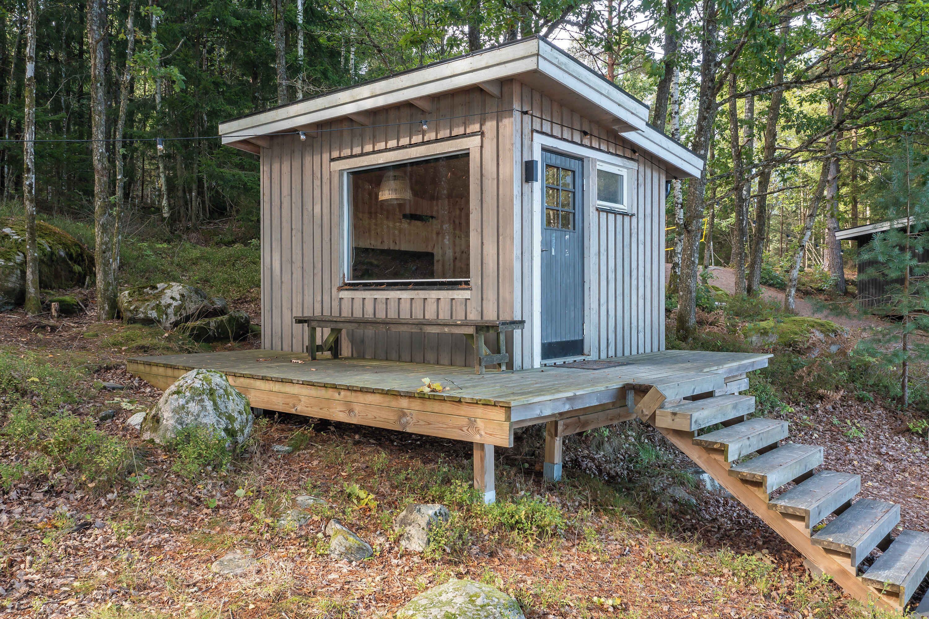 Une cabane en bois dotée d’une terrasse et d’un escalier menant à l’entrée.