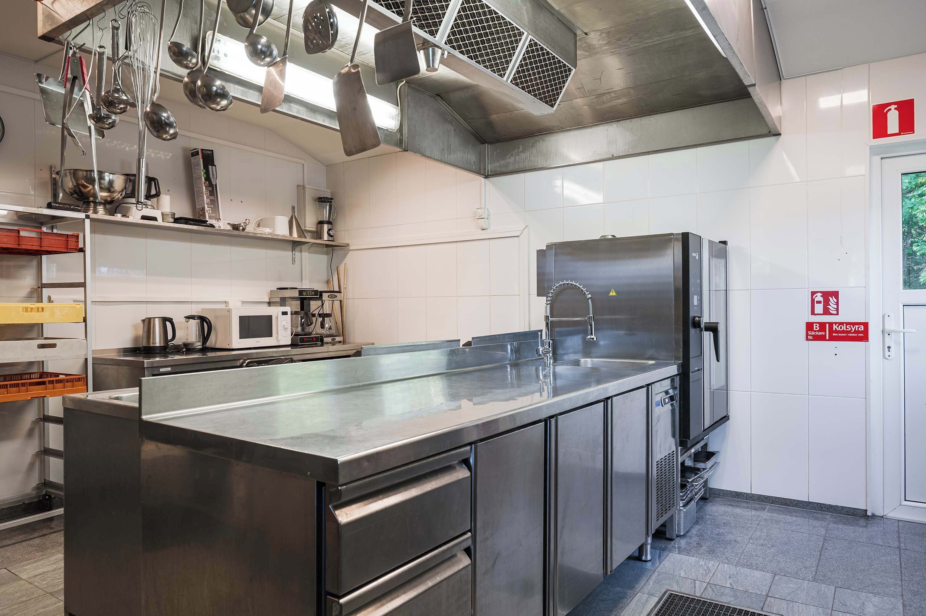 A modern kitchen with stainless steel appliances, a large island, and hanging utensils.